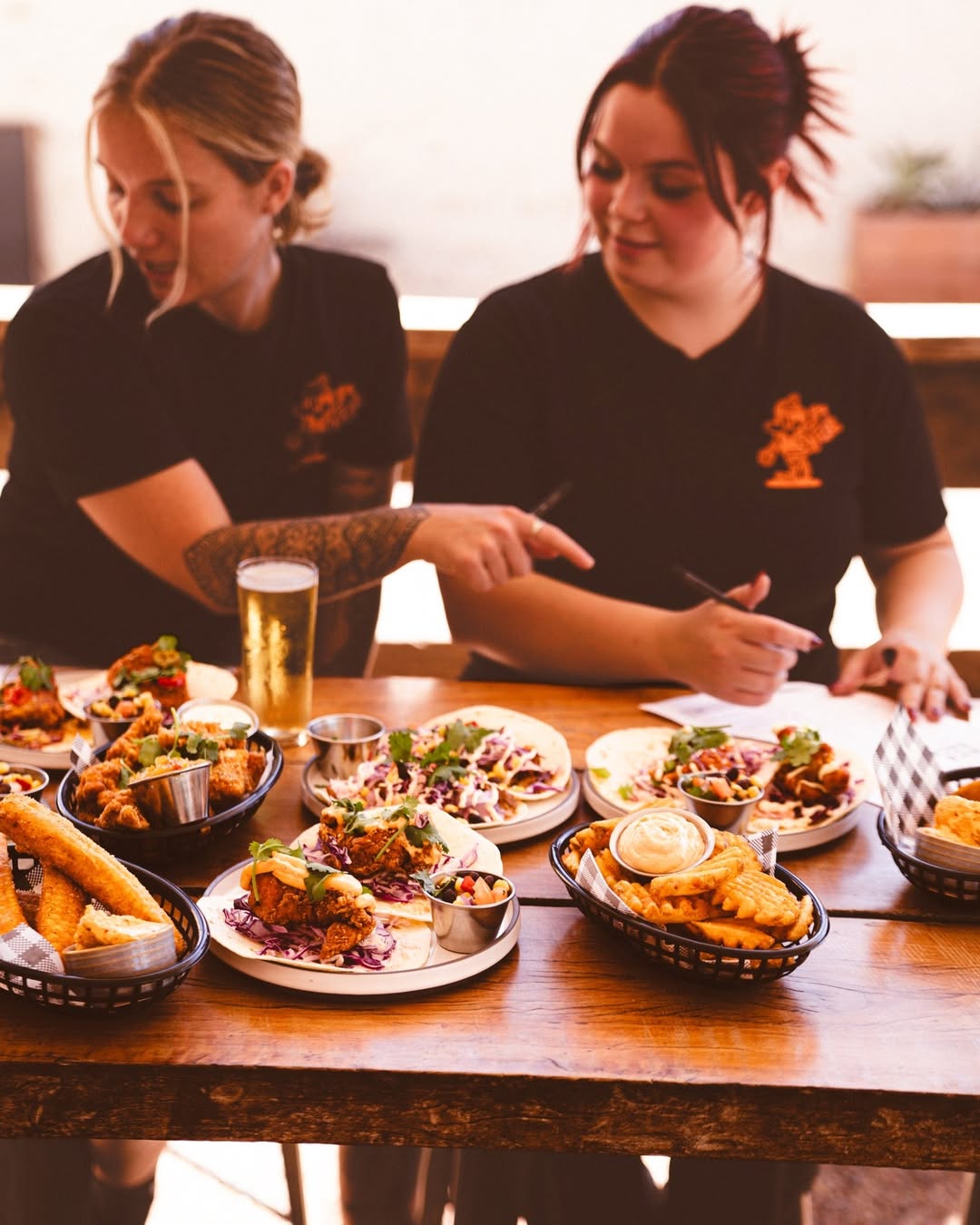 Two people sitting at a table with plates of food and drinks.